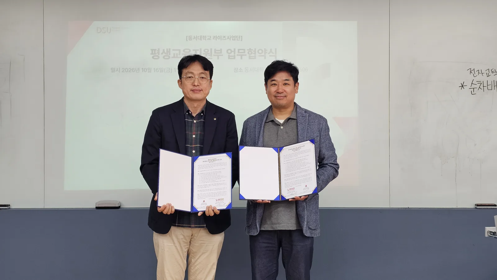한국마술진흥협회(매직카우마술학원)과 동서대학교 관계자가 2026년 10월 16일 업무협약서를 들고 기념촬영을 하고 있다. · 사진 1